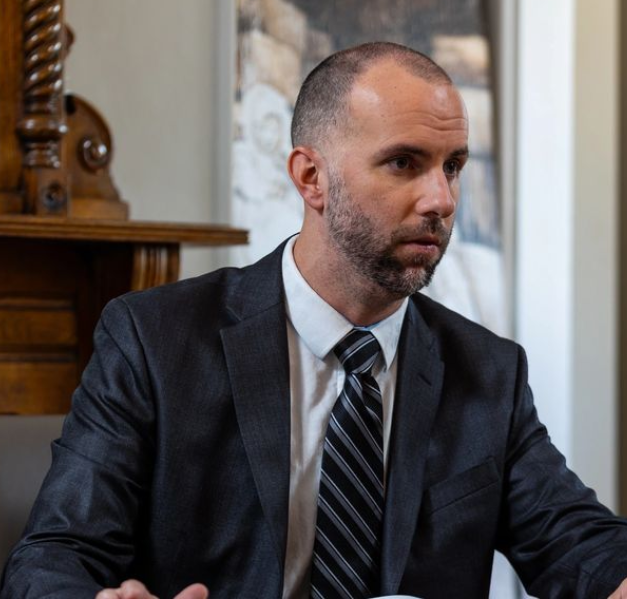 A man in suit and tie sitting at table.