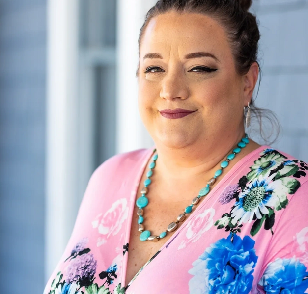 A woman in pink and blue dress standing outside.