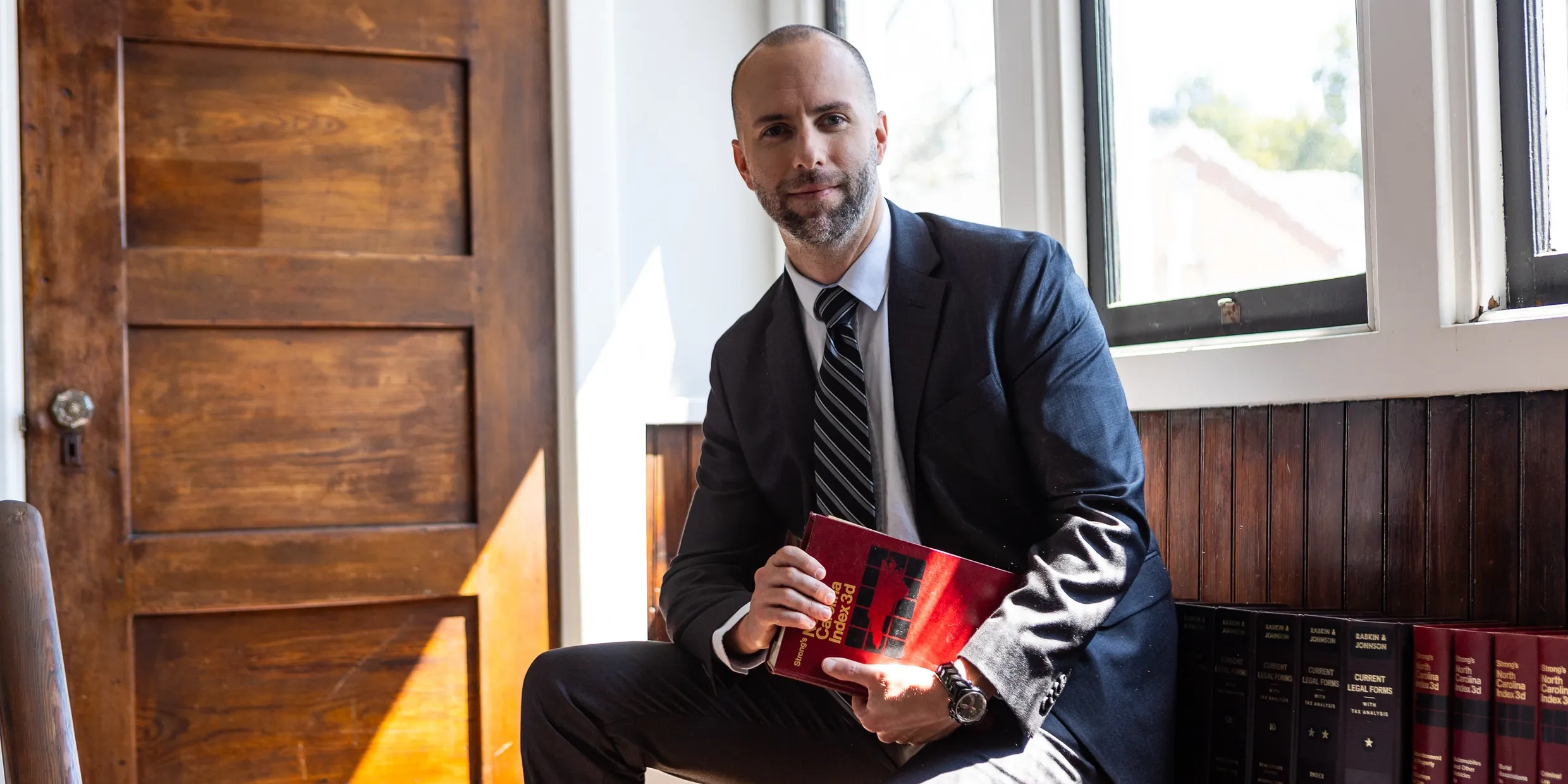 A man in suit and tie holding a book.